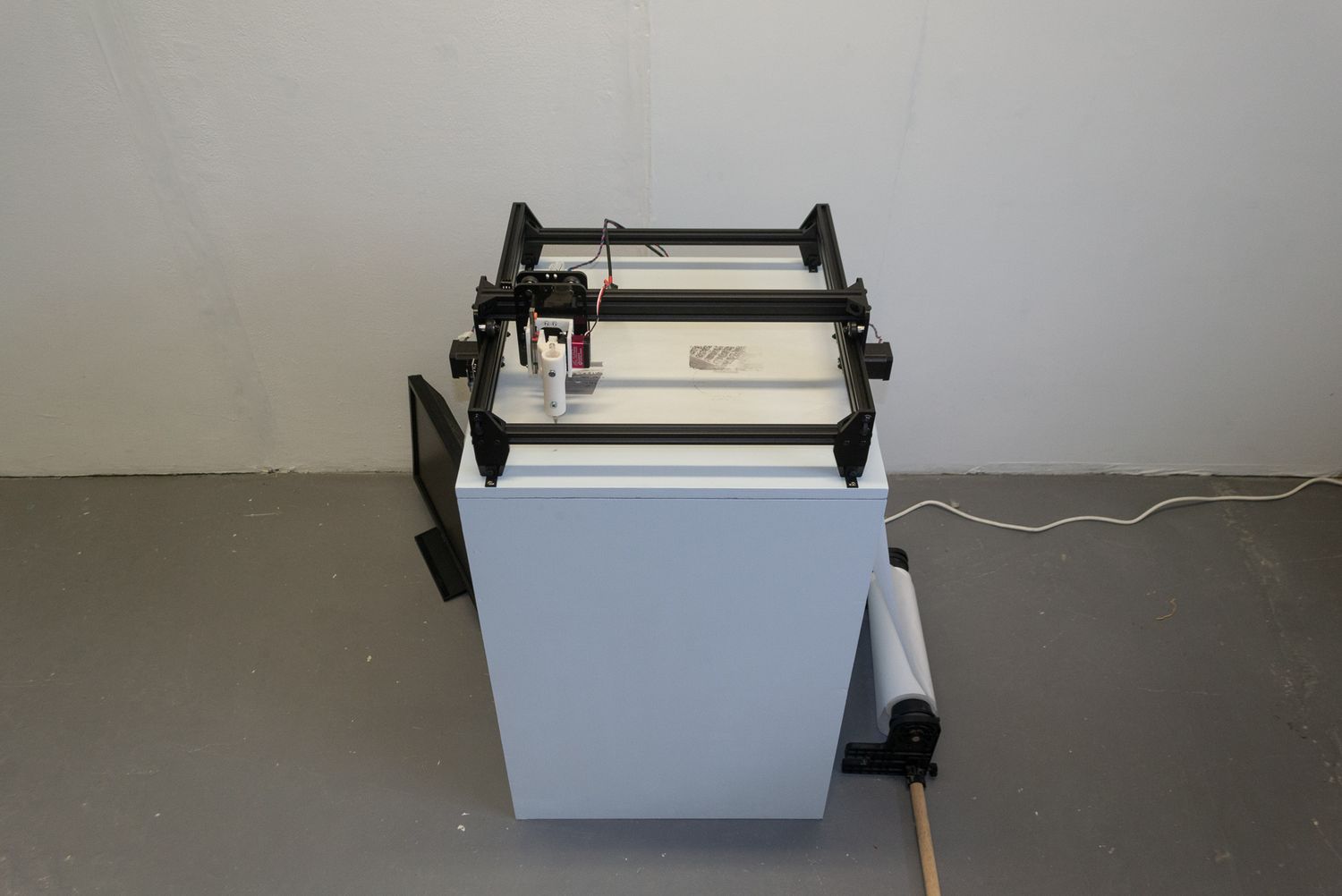 An image of the plotter from Repost; Remake, featuring the screen that displayed the meme currently being drawn at that moment.